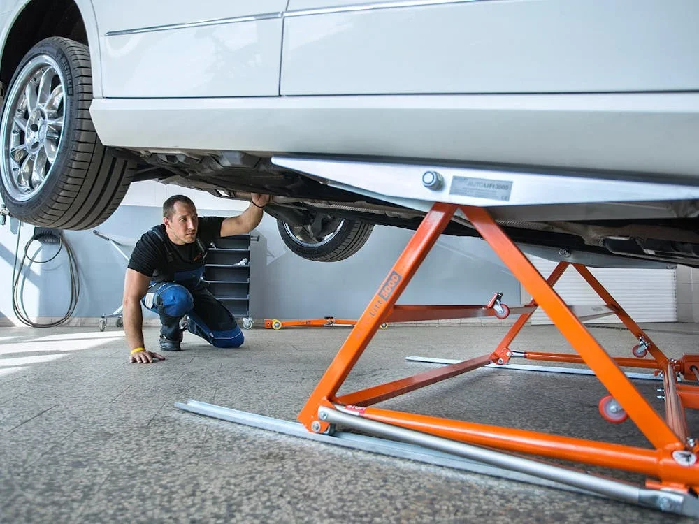 Mechanic inspecting under lifted car